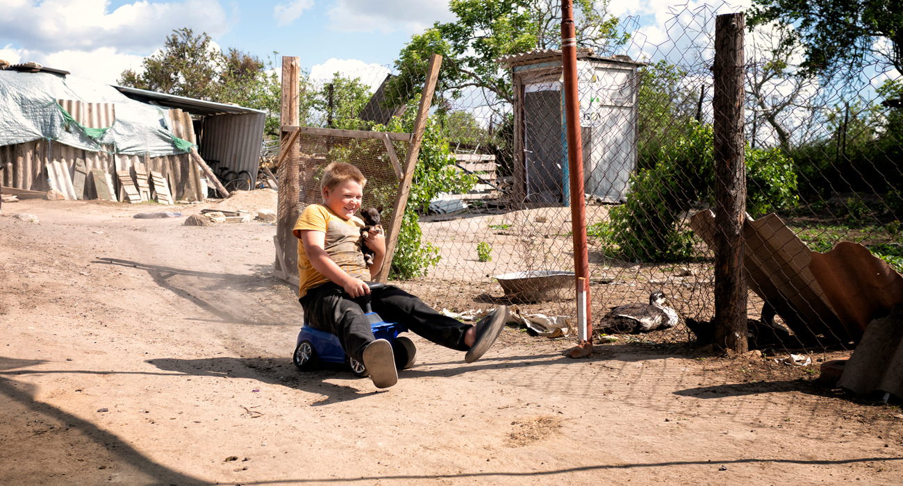 Хлопчик з цуценям катається на машинці на дворі