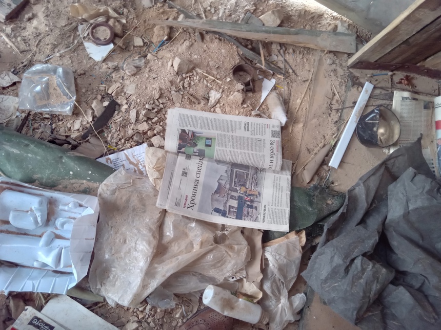 A newspaper lays amongst rubble and dust on the floor