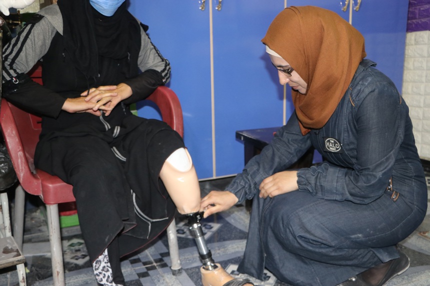 Nour Sheehan, Explosive Accident Support Worker, inspects a woman's prosthetic leg