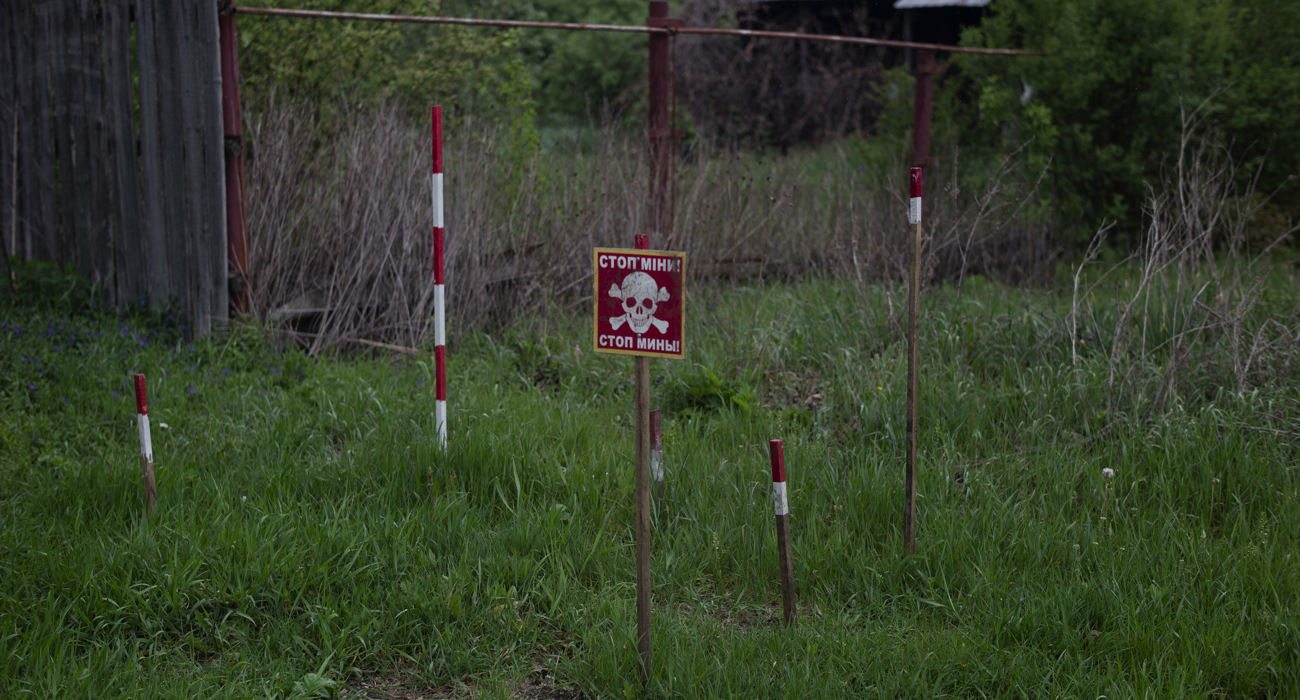 Знак мінної небезпеки та маркувальні віхи мінного поля біля городу