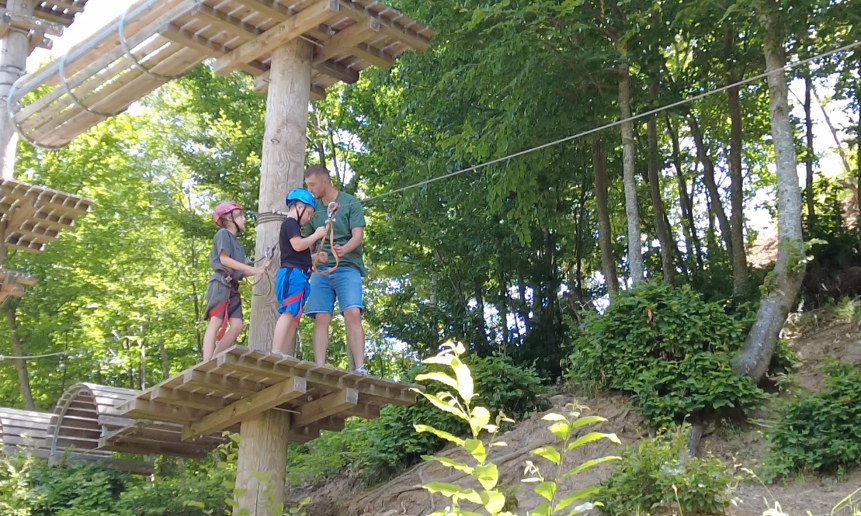 Two children get ready for a high-ropes obstacle course in the trees in Kosovo