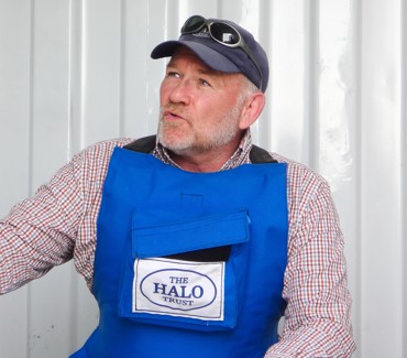 Портрет літнього експерта з розмінування в кепці та темних окулярах на ній з годинником на руці на білому фоні