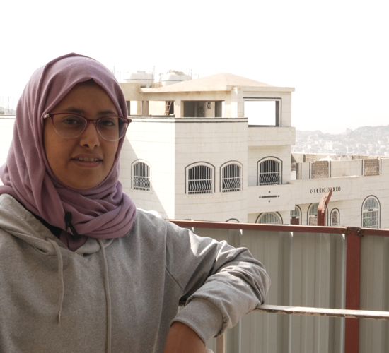 A young woman in Yemen standing on a balcony above Taiz city.