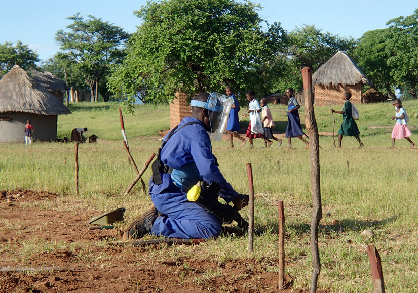 A deminer kneels for an excavation in Zimbabwe