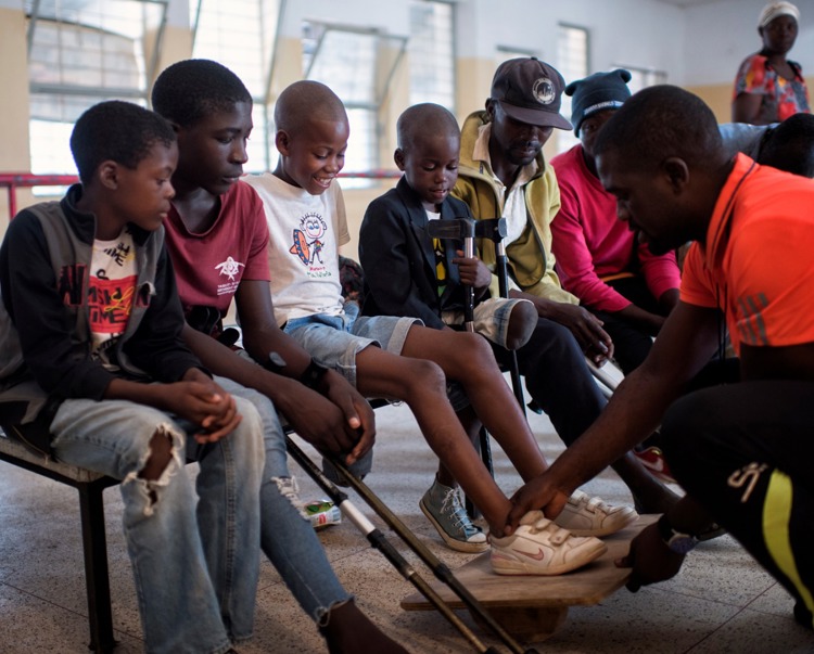 Children sit on a bench during an appointment at the rehabilitation centre