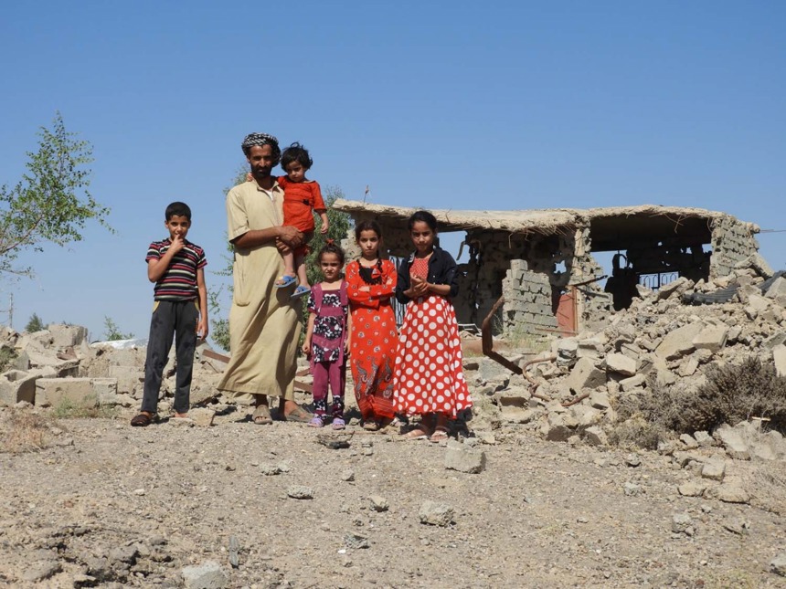 Moshen and his family stand outside their home which has been reduced to rubble