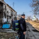 Спеціаліст ХАЛО під час проведення нетехнічного обстеження на фоні розбитих будівель