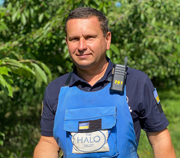 Портрет демінера в захисному спорядженні на фоні зелені і з ягідками в руках