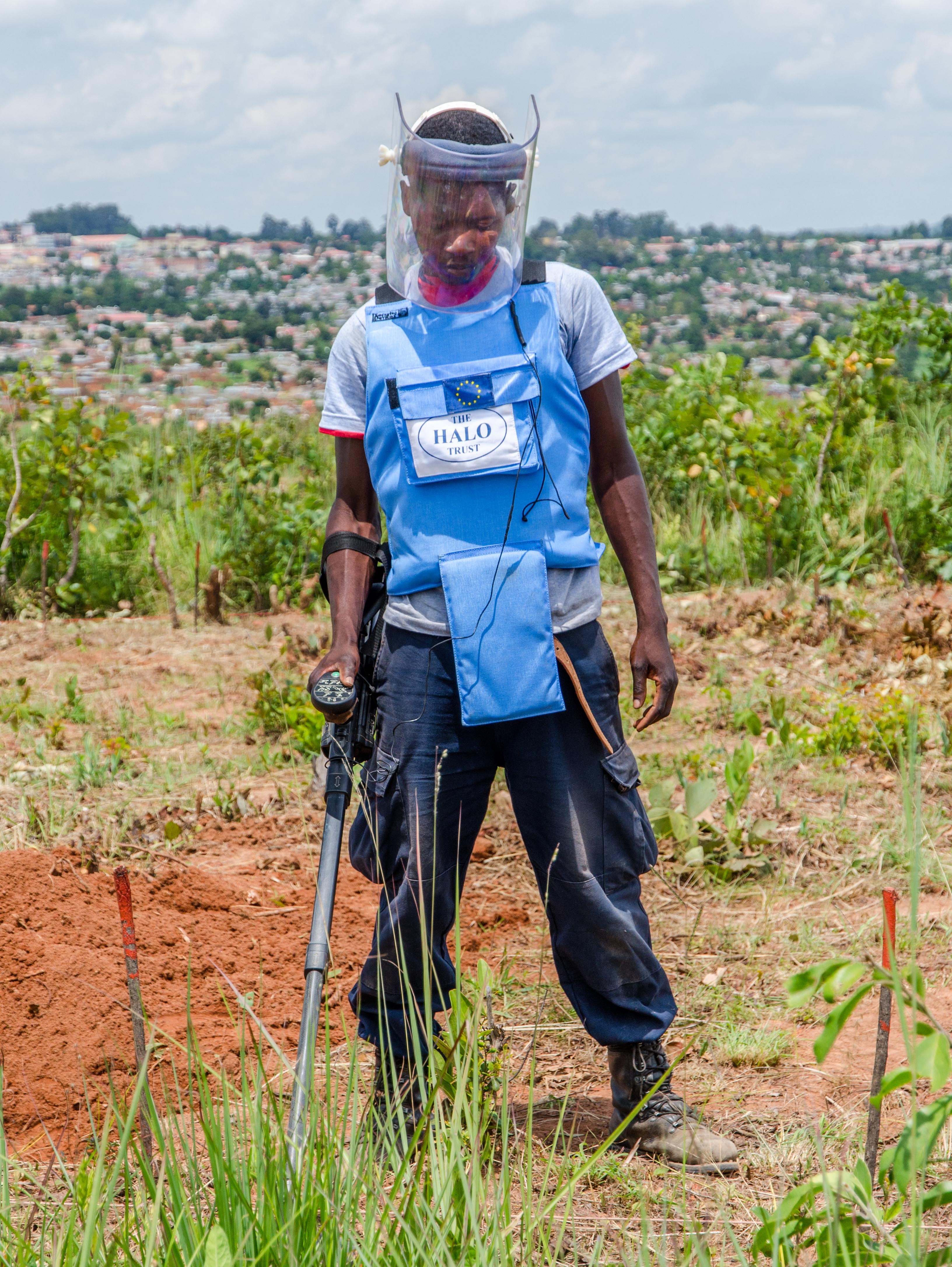 A HALO deminer clearing a minefield at Camissamba, the last but one on the outskirts of Kuito city, visible in the background.