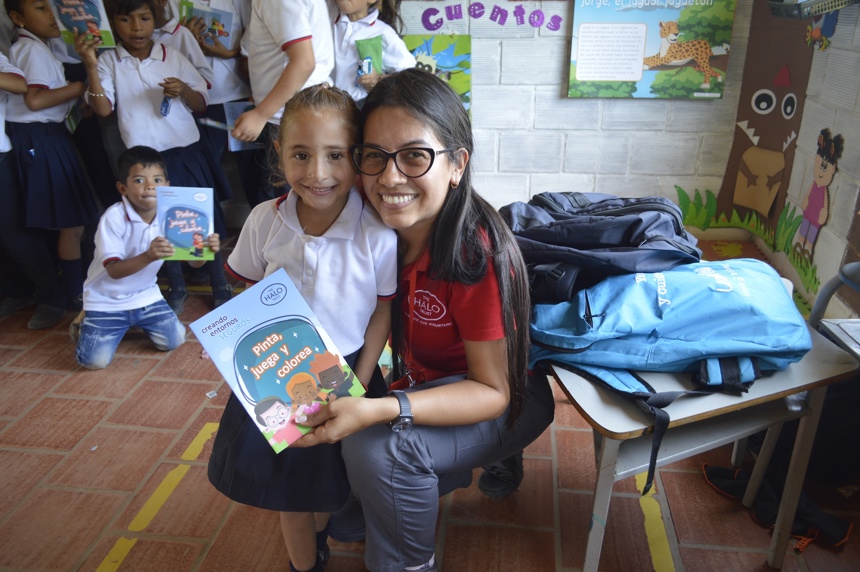 A HALO risk educator poses with a school child in a class after a explosive ordnance risk education session