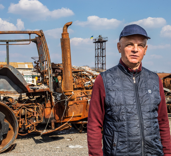 Alexander Mikolaeovich, a Ukrainian farmer, stands in front of his destroyed tractor