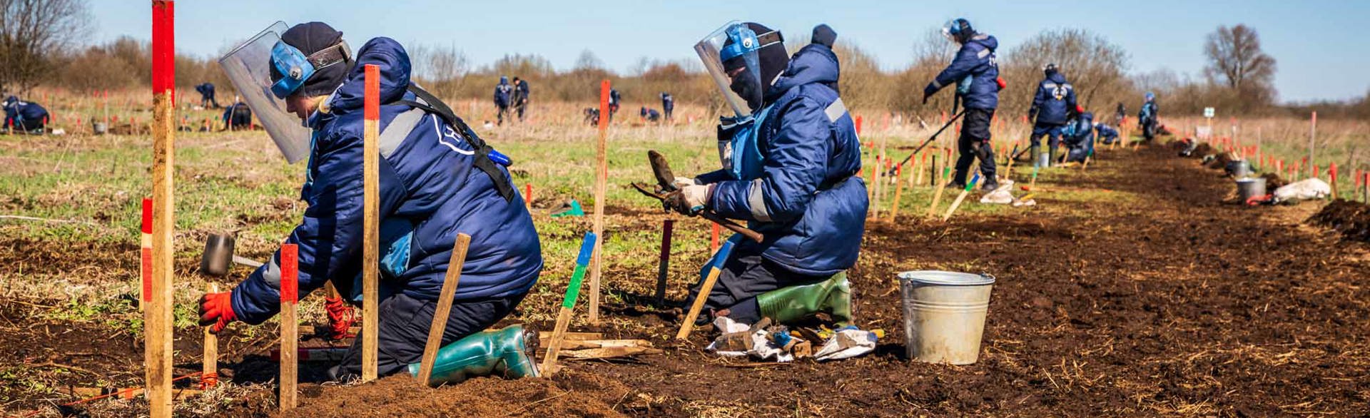Люди в захисному спорядженні, з детекторами та інструментами під час тренінгів з розмінування на відкритій місцевості