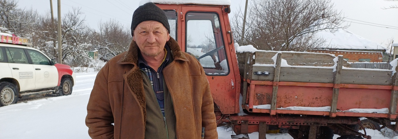 Іван Васильович біля трактора серйозно дивиться в камеру