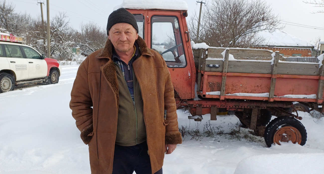 Іван Васильович біля трактора серйозно дивиться в камеру