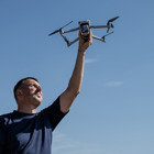 Рука тримає дрон на фоні блакитного неба