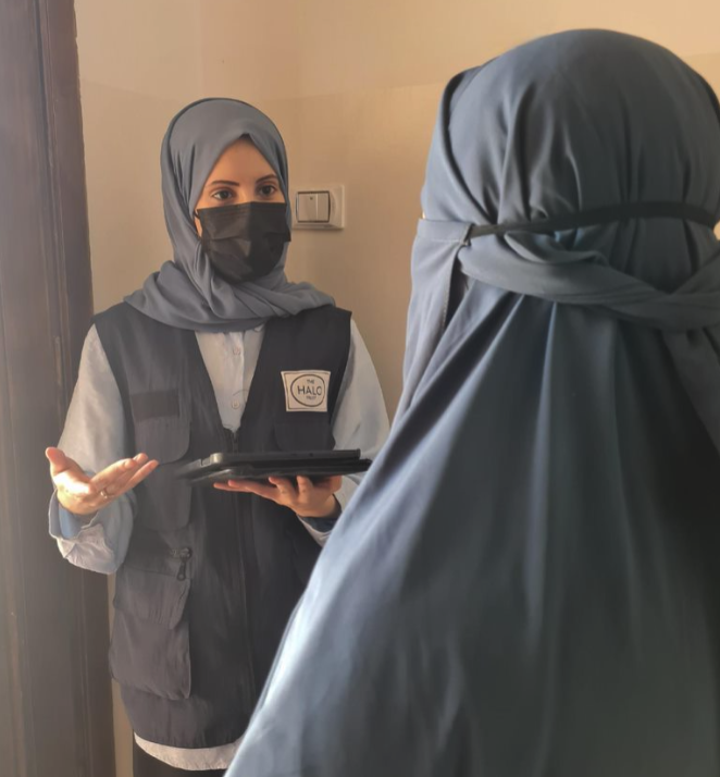 HALO’s Community Liaison Officer speaks with Salha whilst holding a device