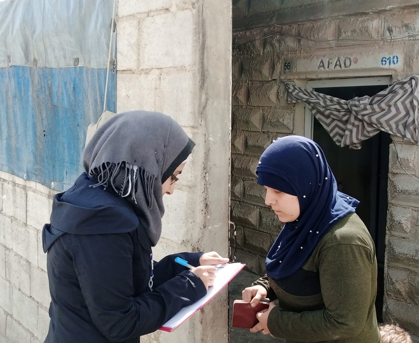  Nour, a case worker assisting victims of conflict, writes on a clipboard as she speaks to a woman outside