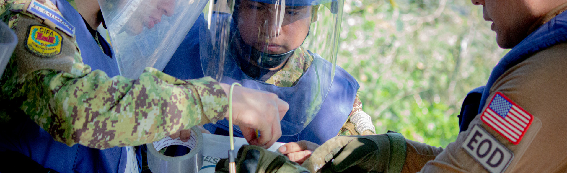 Deminers hold tape and wires as the work on explosive ordnance disposal outside