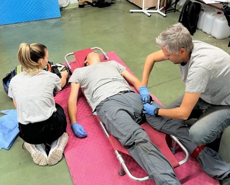 Two staff members attend to a woman on a stretcher for first aid training