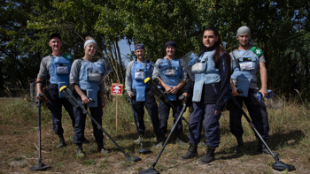 Demining team, in Zolotynka Village, Chernihiv oblast, pose in a minefield with their metal detectors