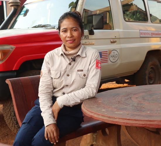 Pat Liv sits outside in front of a HALO vehicle with her elbow resting on a table