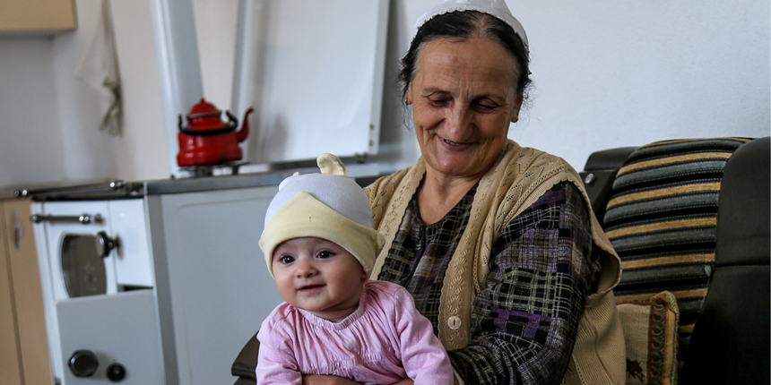 Zejnepe sits in a kitchen with her granddaughter on her lap