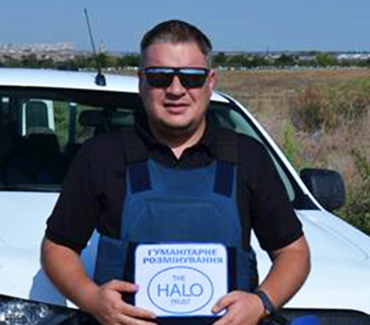 Портрет демінера в захисному спорядженні і темних окулярах на фоні білої робочої машини і поля