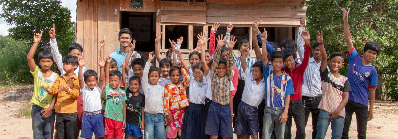 A large group of children waving in Cambodia