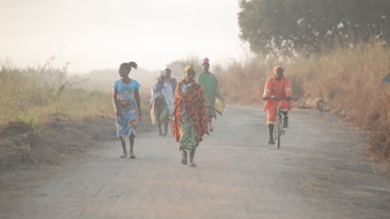 Women in colourful clothes walk along a dirt road in Mozambique