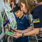 Співробітниця ХАЛО разом з маленьким хлопчиком збирає навчальний пазл "СТОП МІНИ"