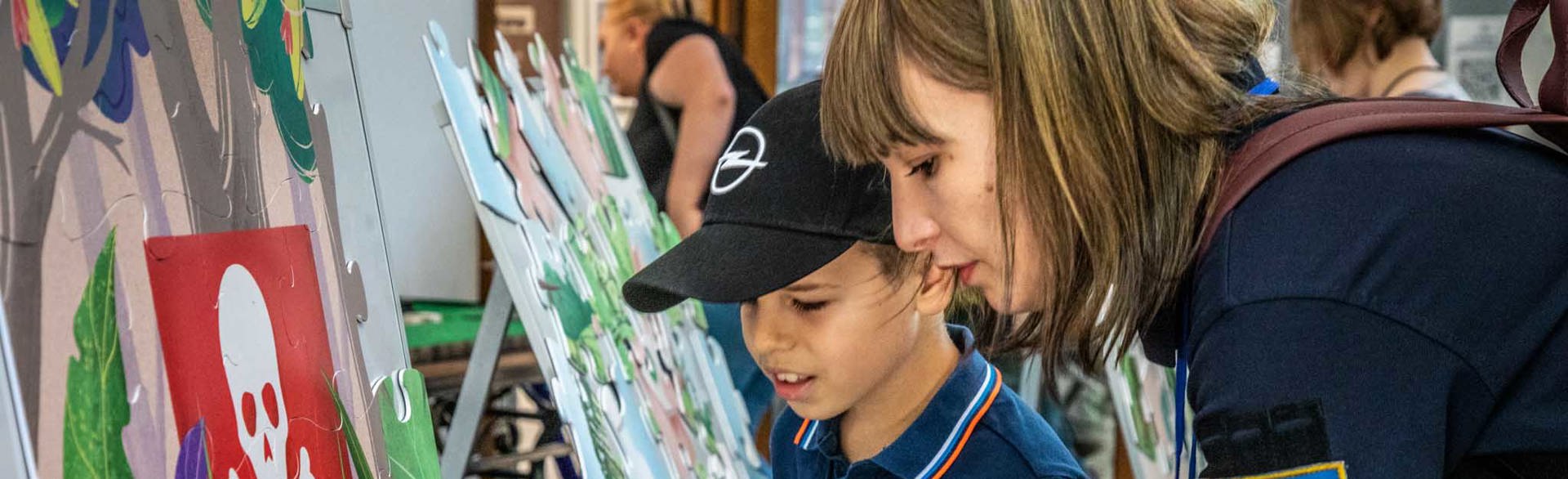 Співробітниця ХАЛО разом з маленьким хлопчиком збирає навчальний пазл "СТОП МІНИ"